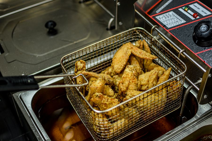 Alitas de pollo fritas en freidora industrial